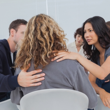 Patients encouraging a woman who is crying during group therapy session
